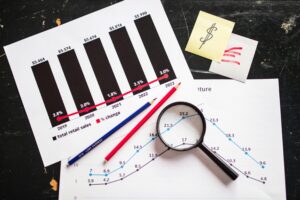 Statistiken ausgedruckt auf einen Tisch mit Lupe und Stiften