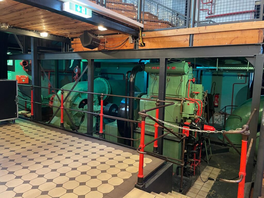 Blick ins Innere des historischen Pumpwerks: Massive grüne Pumpenmaschinen, Rohrleitungen und Ventile zeigen eindrucksvoll die industrielle Technik vergangener Zeiten. Foto: Talea Schmidt