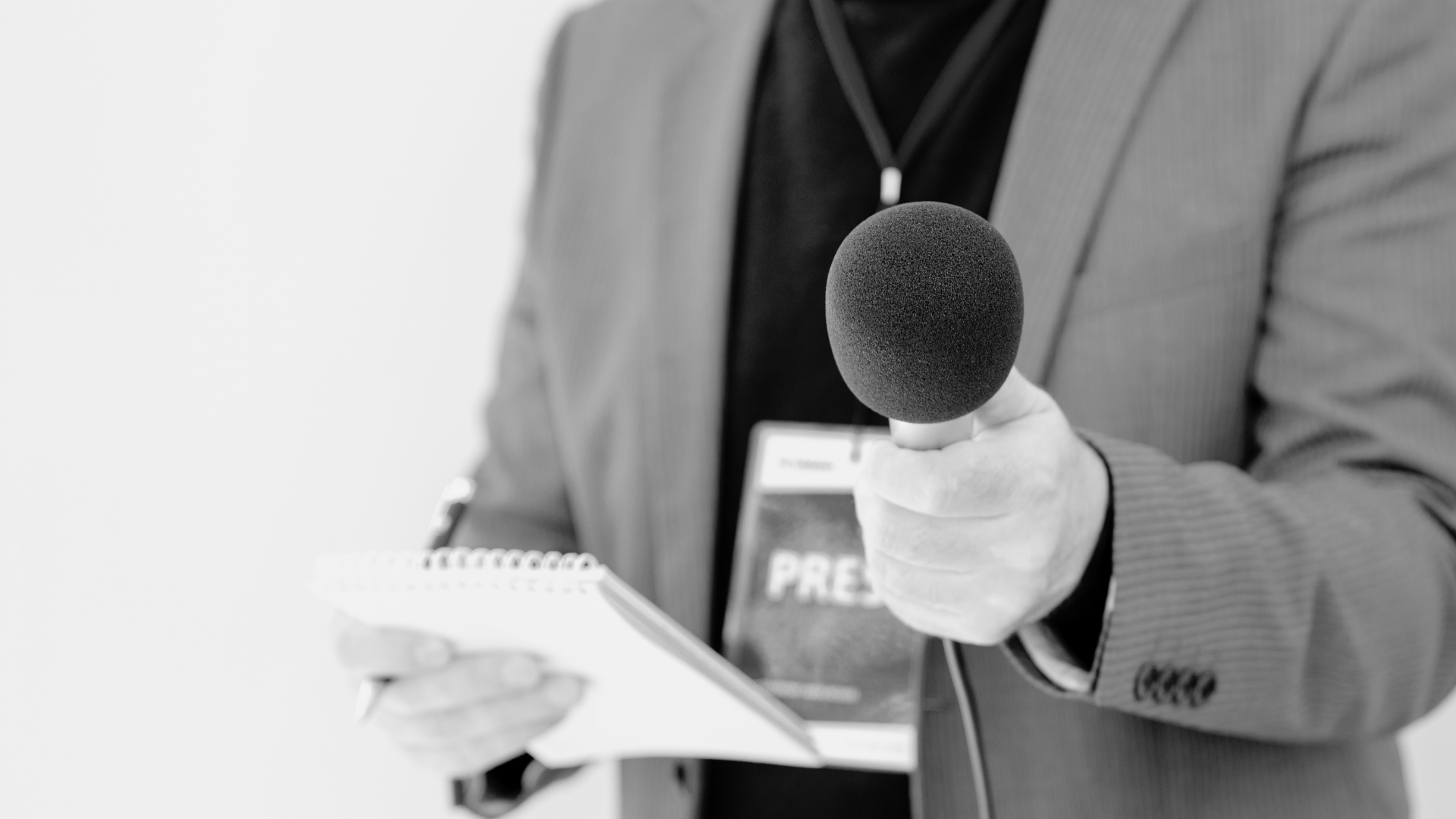 Mann mit Presseausweis hält ein Mikrofon in der Hand