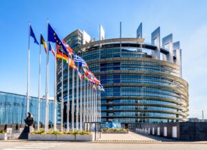 Ansicht des Gebäudes des Europäischen Parlamentes. Glasfassade mit im Wind wehenden europäischen Fahnen.