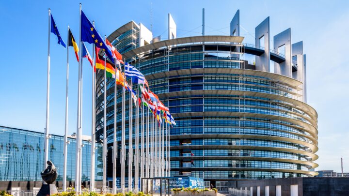 Ansicht des Gebäudes des Europäischen Parlamentes. Glasfassade mit im Wind wehenden europäischen Fahnen.