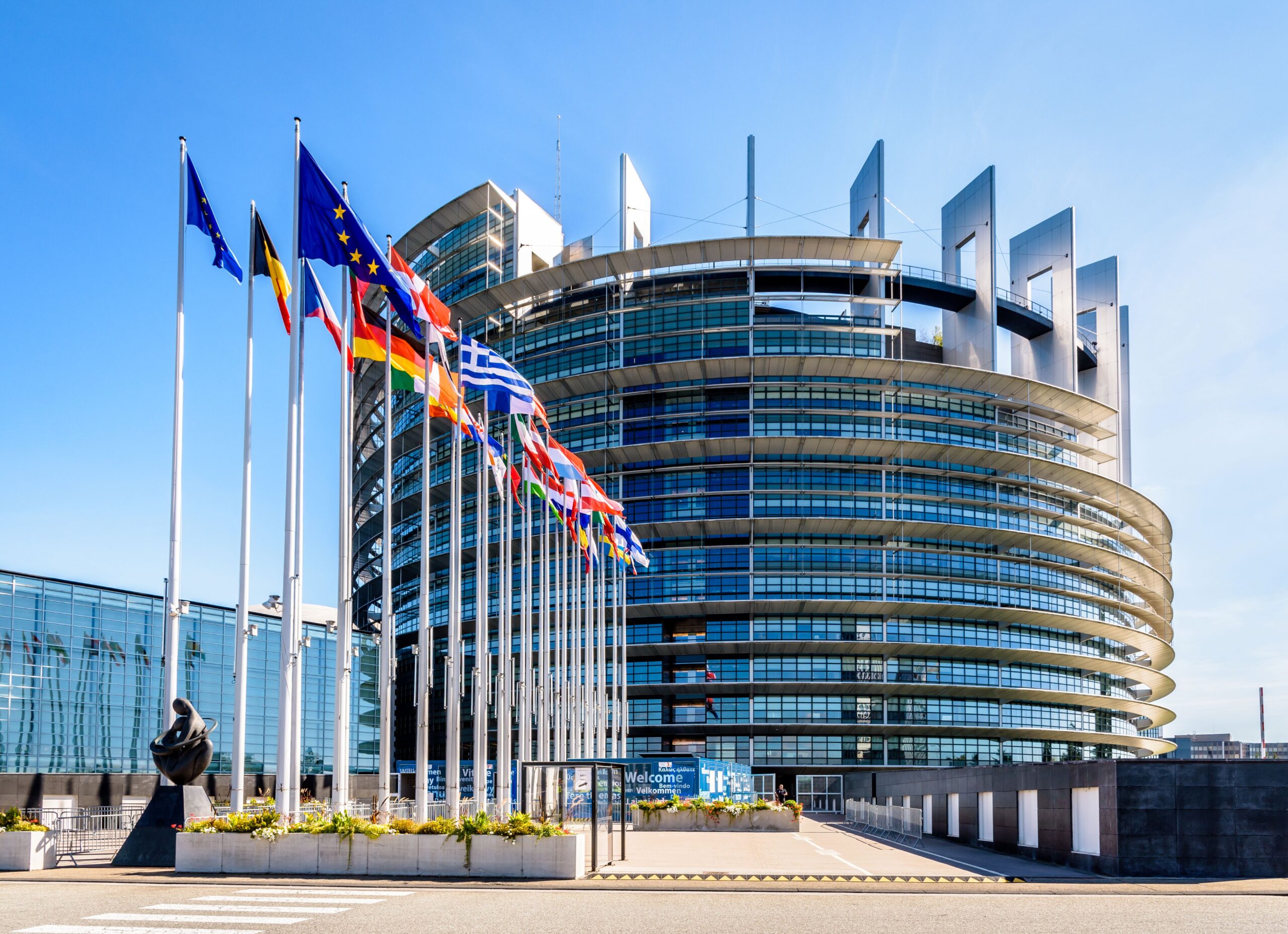 Ansicht des Gebäudes des Europäischen Parlamentes. Glasfassade mit im Wind wehenden europäischen Fahnen.